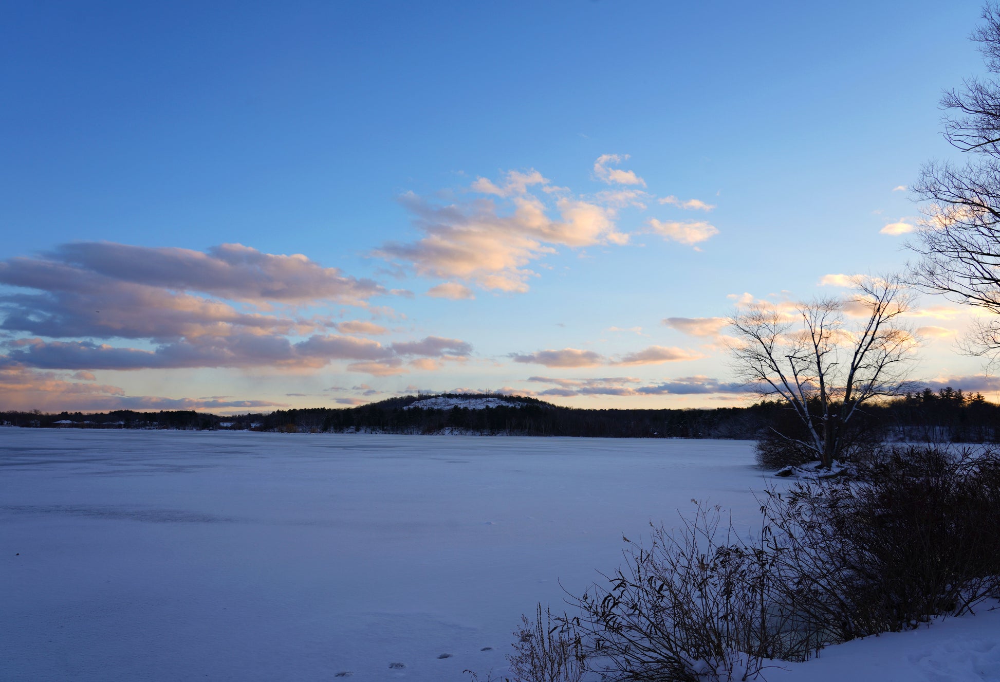 greeting card Frozen lake with snow-covered ground and trees at sunset.